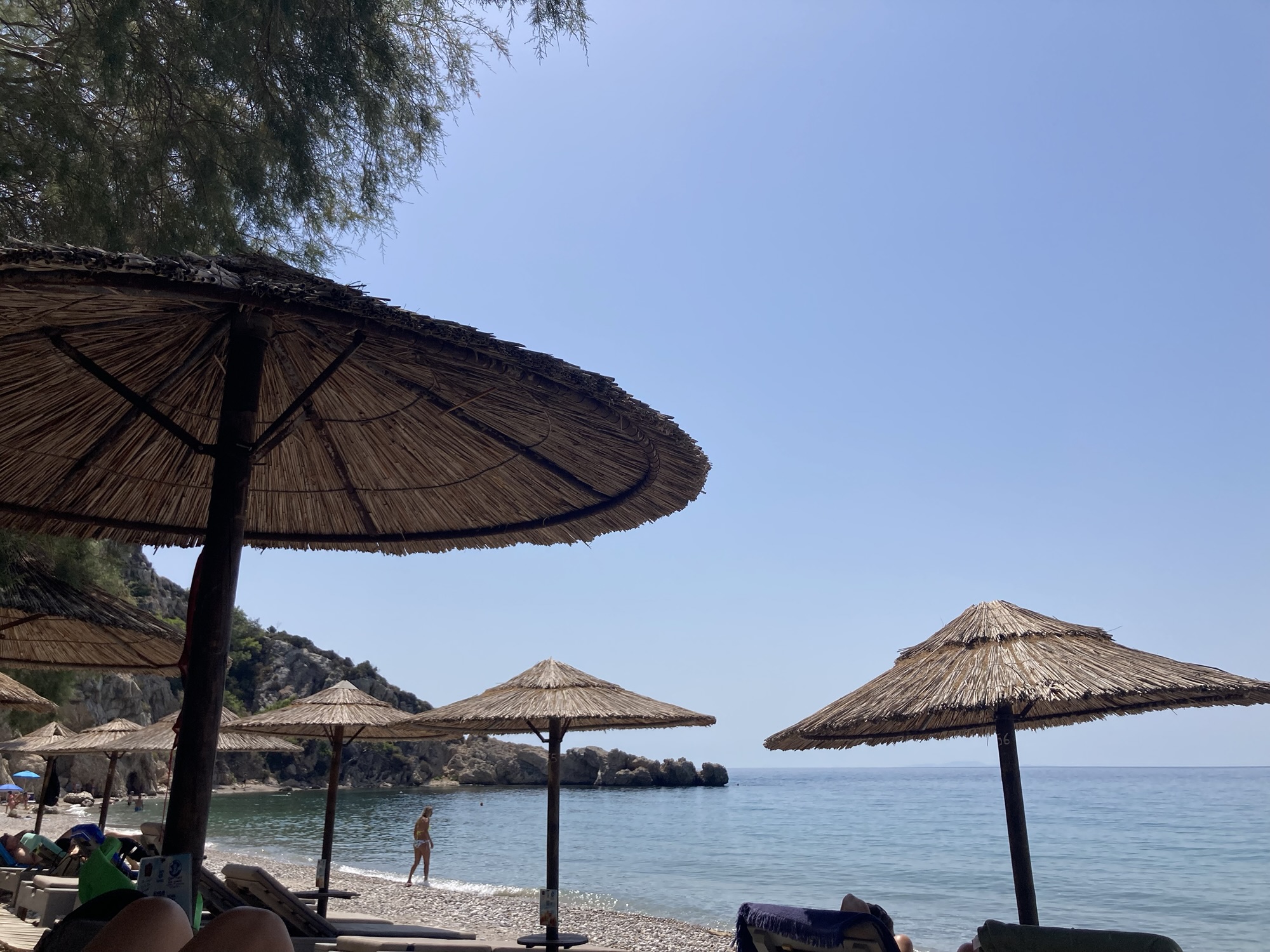 stranden op samos met blauwe zee en ligbedden