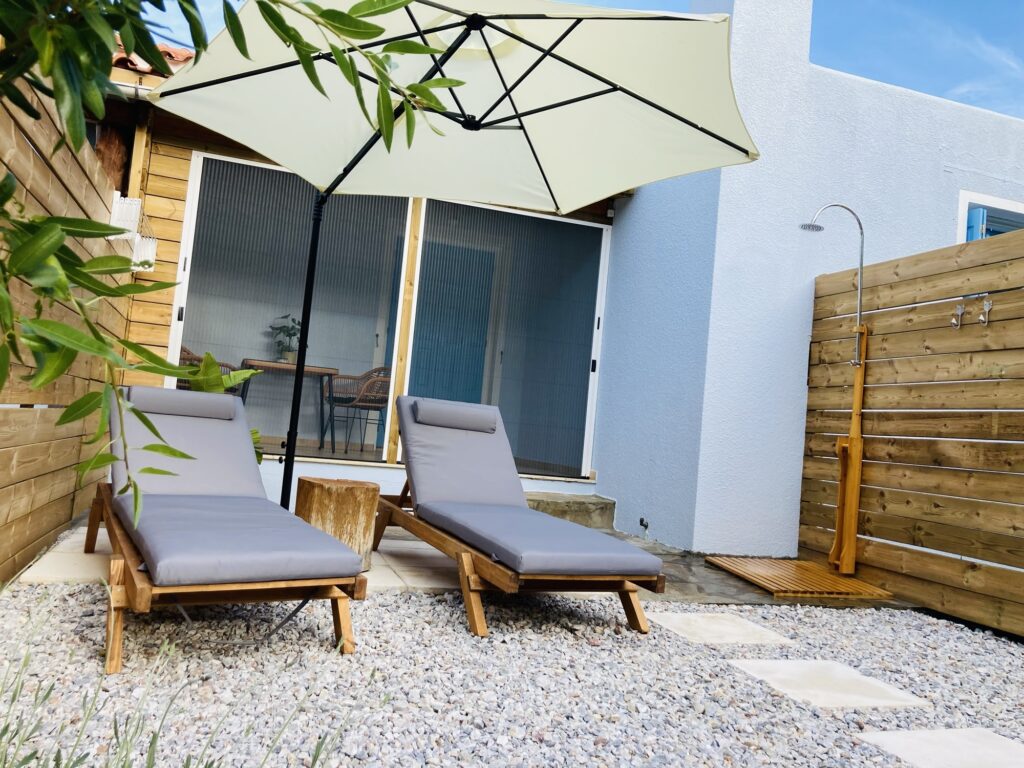 The garden of bougainvillea holiday home on samos with two sunloungers, a parasol, covered terras and outdoor shower