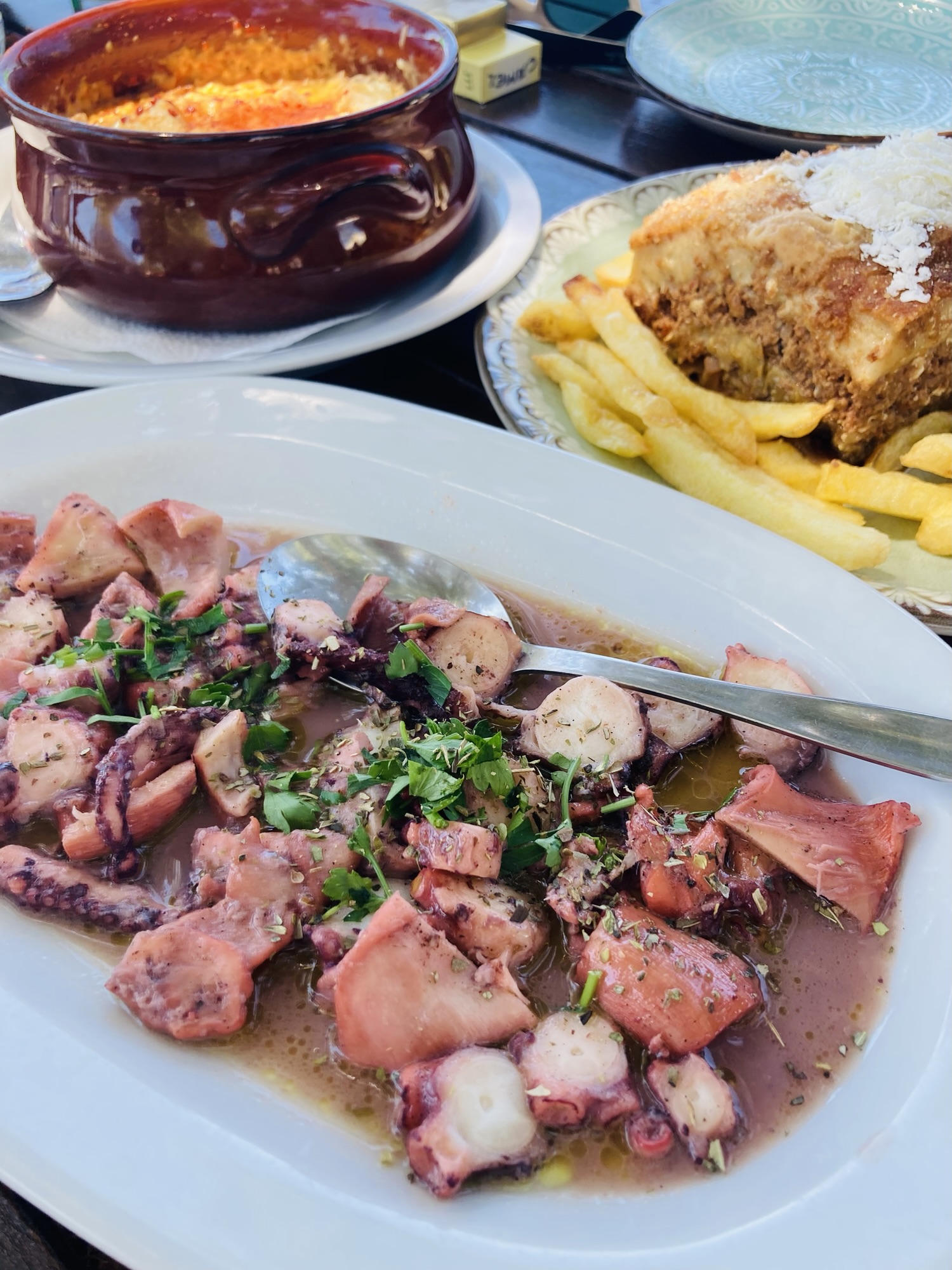 a table with a plait with octopus, mousaka and other food at a restaurant in Mykali on Samos